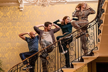 Vier der Schauspieler werfen sich in eine synchrone Tanzposition auf der Treppe